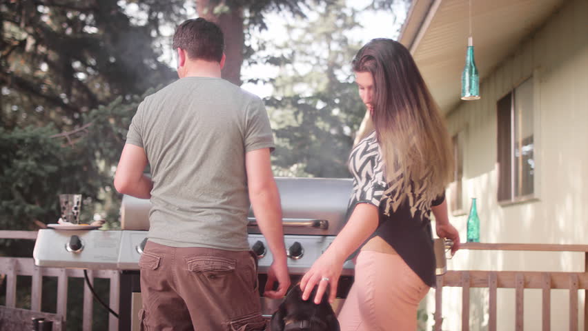 A Husband And Wife On Their Porch Barbecuing And Petting Their Dog ... photo picture