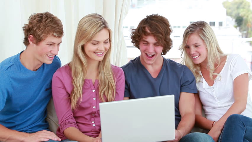 Happy Young Man Singing With A Microphone Against Grey Happy Friends Laughing In Front Of A Laptop Bright Living Room Hd Stock