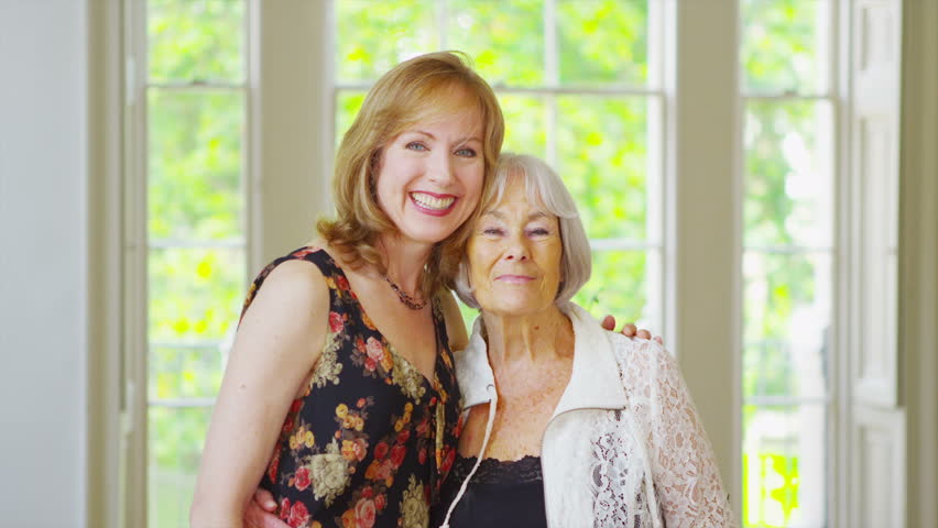 Mother And Adult Daughter Hugging And Smiling At Camera In The Park On