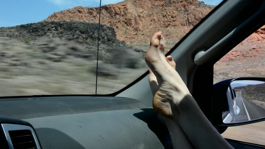 Womans Feet Propped On The Dashboard Of A Car While Driving Through A