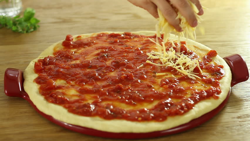 putting-cheese-topping-on-pizza-dough-already-coated-with-tomato-sauce