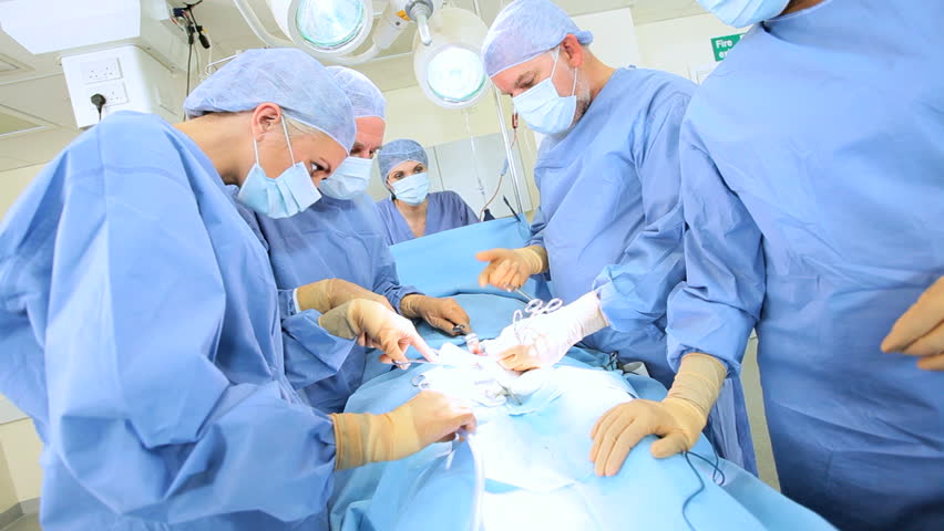 Multi Ethnic Surgical Team In Protective Clothing Performing Surgery ...