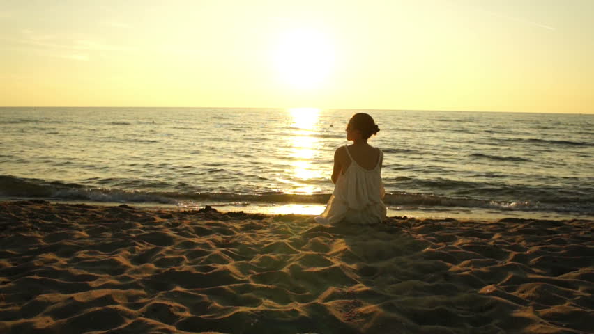 Woman Sitting On A Sand Beach In Front Of Sunset And Ocean In Summer ...